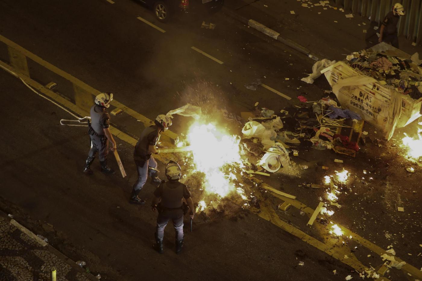 La polizia brasiliana cerca di spegnere l'incendio di una barricata per le strade di Brasilia